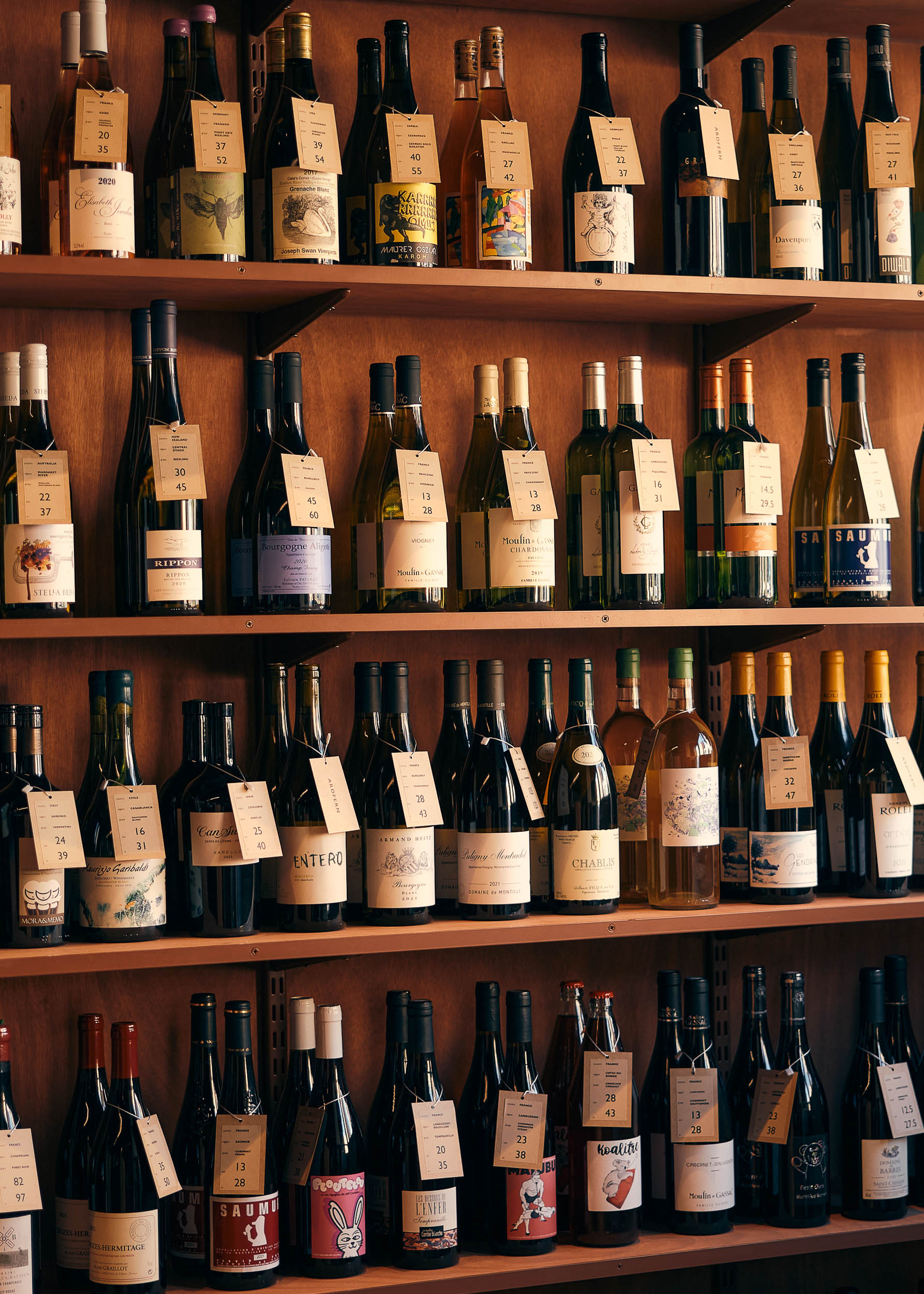 Ardfern&rsquo;s wine wall — wooden shelves stacked with bottles from the hundred-strong list