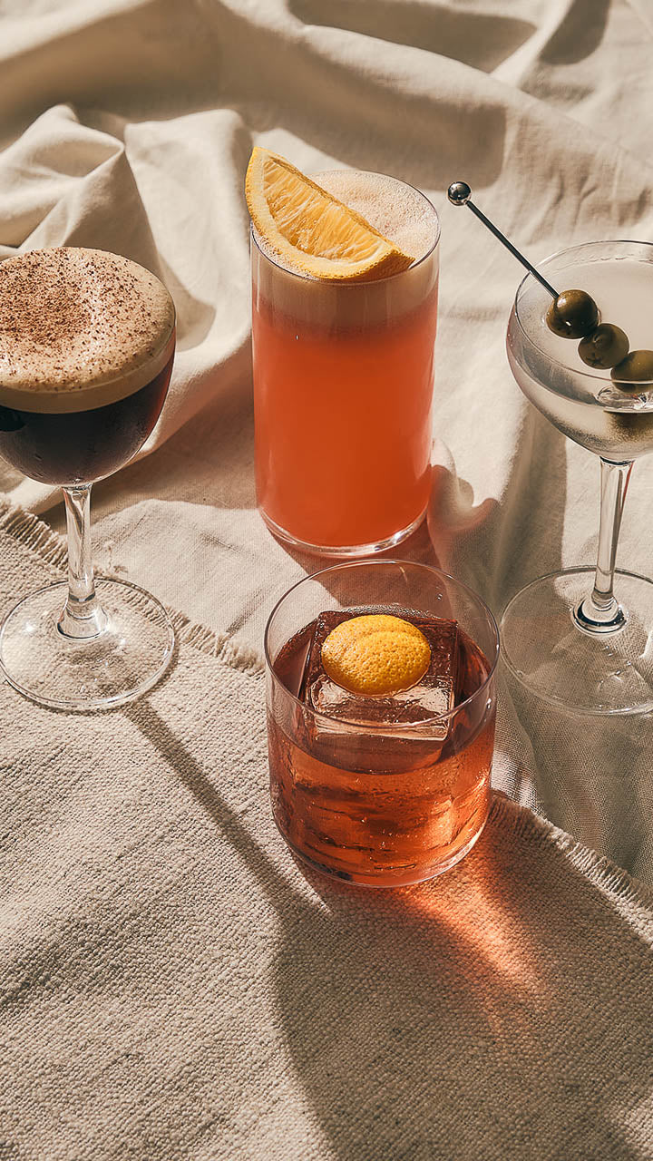 Cocktails catching the sun on a linen-covered table