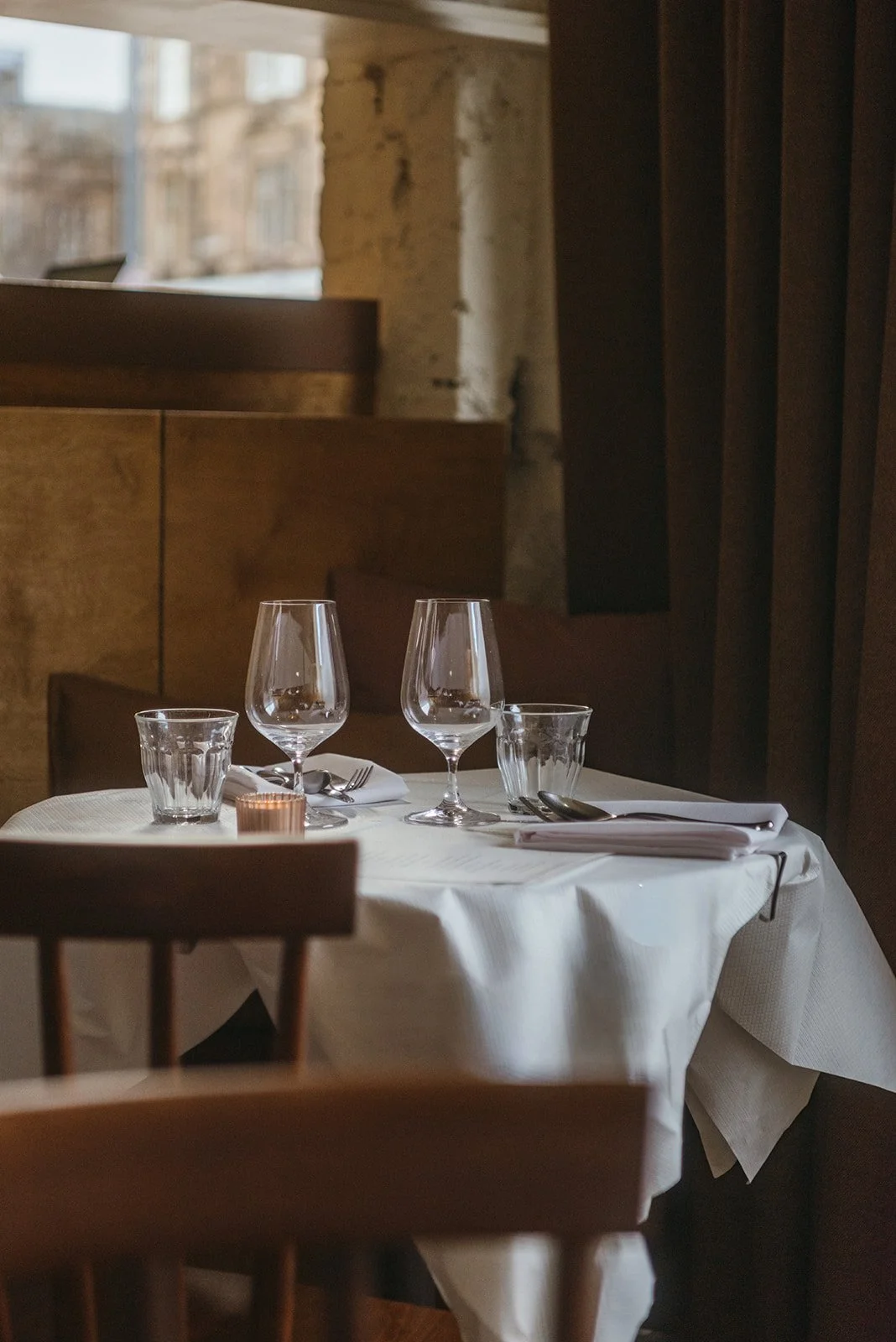 A candlelit, white-clothed table set for dinner at eleanore