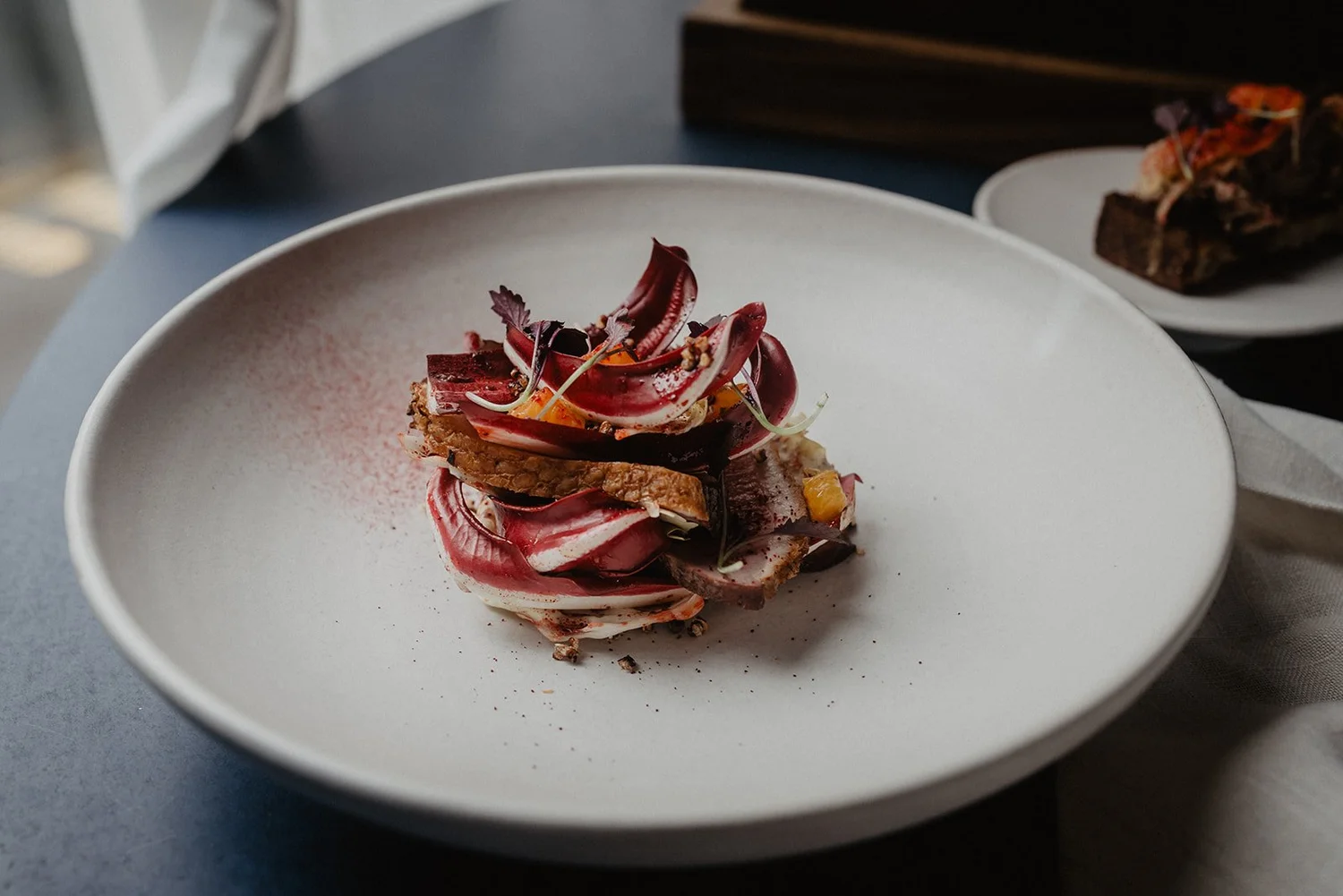 Charred radicchio dish plated on white against the navy table