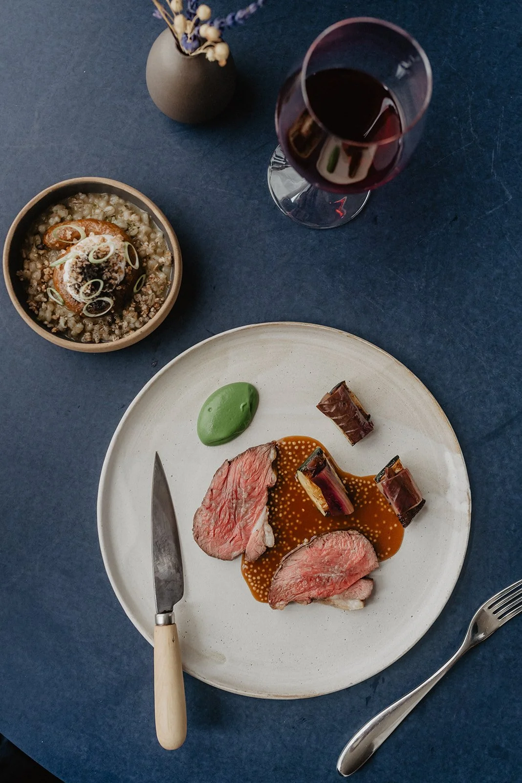 Sliced roast meat with a green emulsion on a white plate